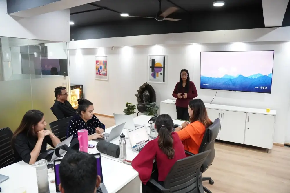 Digital marketing team meeting in modern conference room with presentation display and collaborative workspace